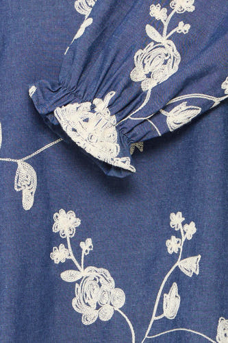 Blouse bleue à longues manches en Fransa, avec des motifs de broderie de fleurs blanches et une finition de manche pliée.