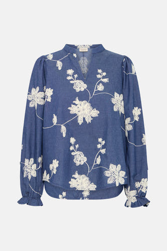 Blouse bleue à longues manches en France, avec des motifs floraux brodés et des volants aux extrémités des manches.