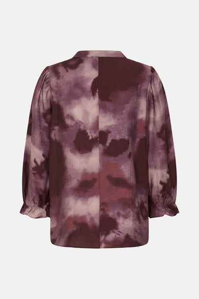 Blouse rouge à longues manches de France, avec un motif tacheté et des manches bouffantes.