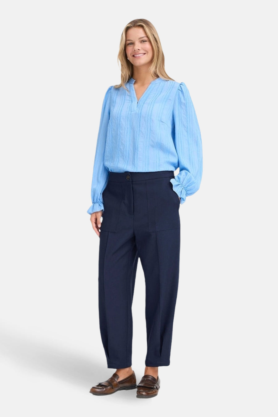 Blauwe broek van Fransa met rechte pijpen en zakken, gecombineerd met een lichtblauwe blouse en bruine loafers.
