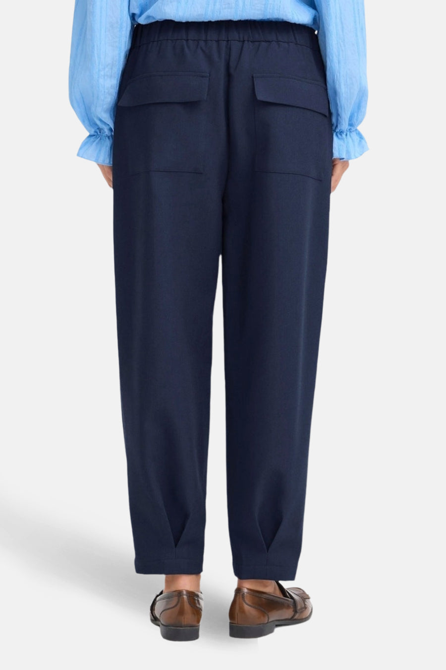 Blauwe broek van Fransa, met twee opgestikte achterzakken en bruine schoenen.
