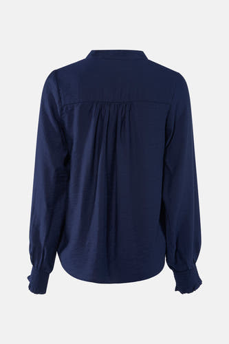 Blouse bleue à longues manches en France, avec des plis et du smockage aux poignets, vue de derrière.
