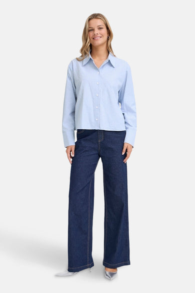 Bleu, chemise à longues manches de France, portée avec une subtile texture sur des jeans foncés.