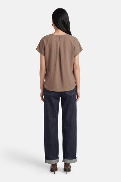 Beige blouse met korte mouwen van Fransa, gezien van achteren, gecombineerd met donkere jeans en hakken.