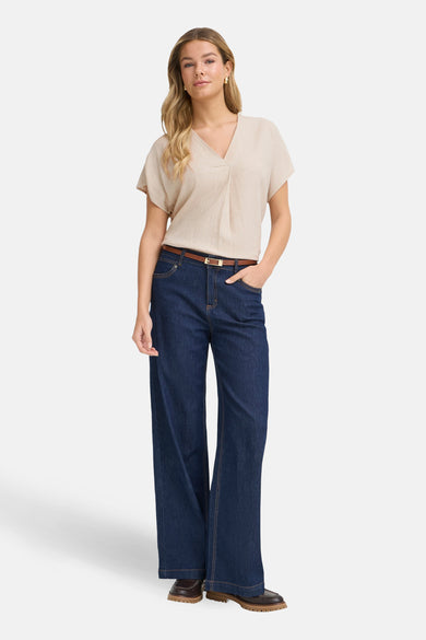 Chemisier beige à manches courtes de Fransa®, uni, avec col en V et porté avec un jean bleu foncé et une ceinture marron.