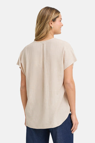 Chemisier beige à manches courtes de Fransa, avec des plis au dos et porté avec un pantalon foncé.