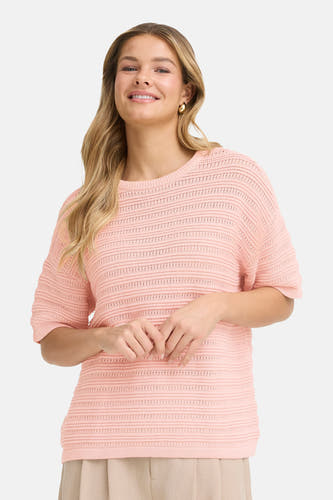 Pull rose à col rond de Fransa, avec détails ajourés et associé à un pantalon beige large et des escarpins pointus foncés.