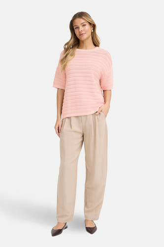 Roze trui met ronde hals van Fransa, met opengebreide details en gecombineerd met beige, wijde pantalon en donkere punt pumps.
