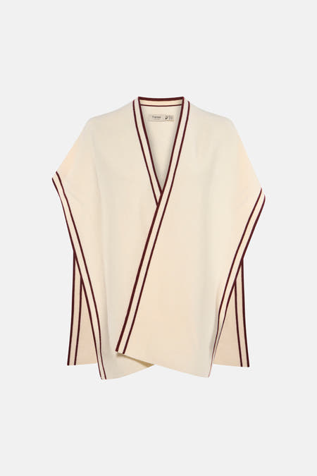 Gilet écru de Fransa, avec des rayures bordeaux le long des bords, combiné avec un col roulé beige et un pantalon noir ample.