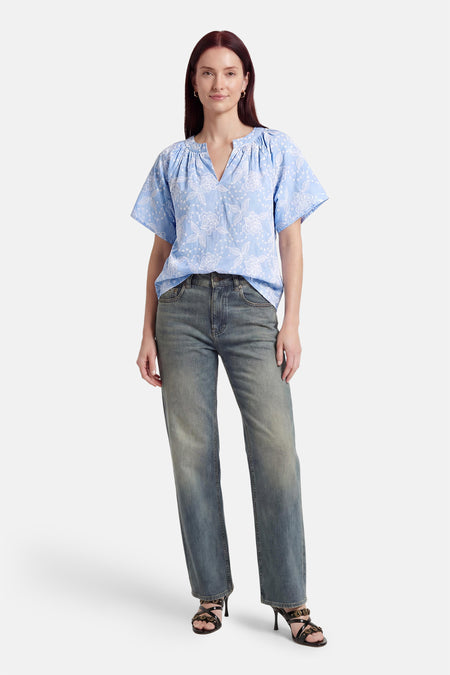 Chemisier bleu à manches courtes de Fransa® avec broderie florale blanche, col en V, à combiner avec un jean et des talons noirs.