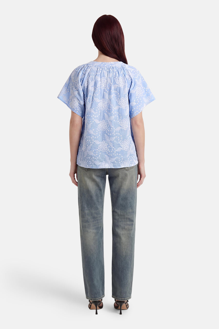 Chemisier bleu à manches courtes de Fransa avec broderie florale blanche, vu de dos. Porté avec un jean délavé et des talons noirs.