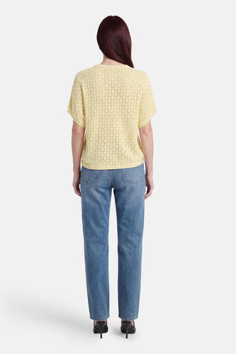 Gele pull met ronde hals van Fransa, met opengewerkt ruitpatroon, gedragen over een blauwe jeans en zwarte hakken, achteraanzicht.