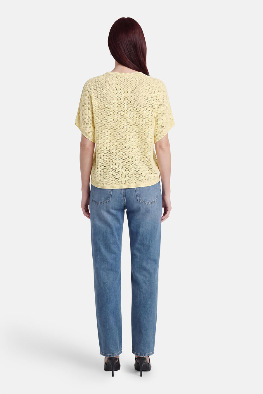 Gele pull met ronde hals van Fransa, met opengewerkt ruitpatroon, gedragen over een blauwe jeans en zwarte hakken, achteraanzicht.