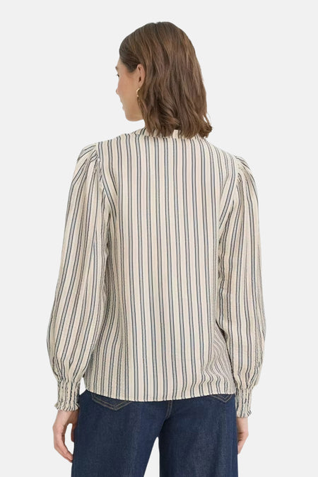 Ecru blouse met lange mouwen van Fransa, met gestreepte print en gerimpelde manchetten, gedragen met een donkerblauwe jeans.
