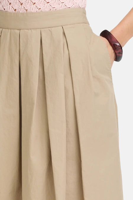 Bruine lange rok van Fransa® met plooien en elastische taille, close-up van voorkant met hand in zak