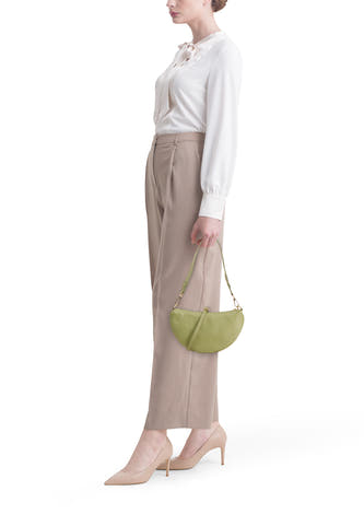 Sac bandoulière vert pour femme Access®, forme demi-lune, en cuir texturé, porté par un mannequin avec une blouse blanche et un pantalon beige.
