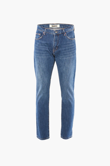 Jean tapered bleu de WOODBIRD, vu de l'arrière, avec un léger lavage et une étiquette en cuir marron.