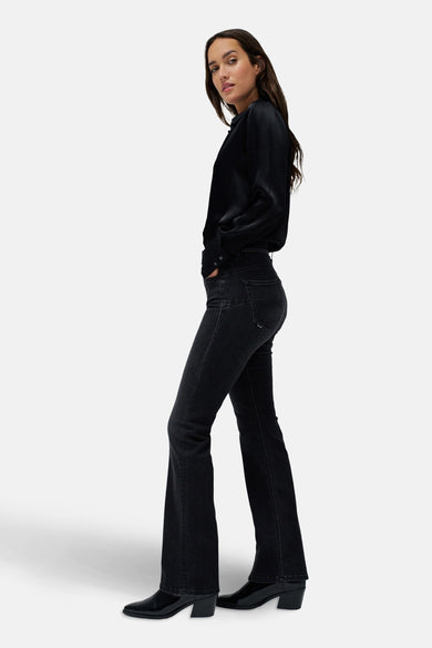 Jean bootcut en denim gris foncé de Salsa Jeans, avec des détails subtils et associés à une blouse noire et à des bottes.