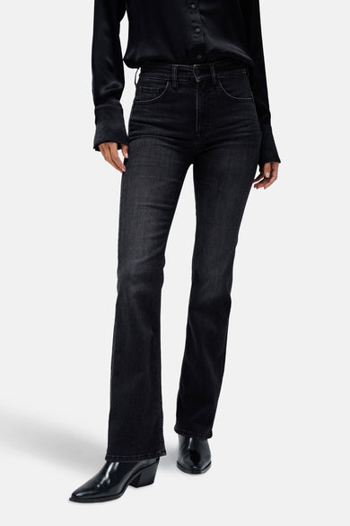 Jean bootcut en denim gris foncé de Salsa Jeans, avec une légère ligne qui s'élargit et des bottes noires en cuir.