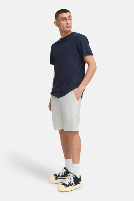 Crèmekleurige linnenlook short van SOLID met trekkoord taille, gedragen door een man in donkerblauw T-shirt en sneakers.
