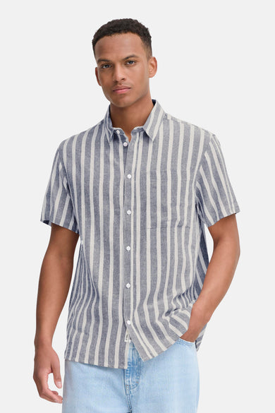 Chemise rayée bleue de SOLID, à manches courtes et portée avec un jean bleu clair et des baskets blanches.