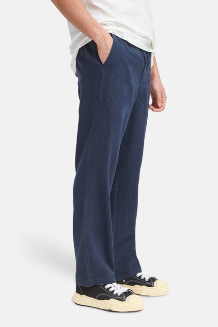 Pantalon bleu de SOLID, avec une coupe décontractée et porté avec un t-shirt blanc et une chemise.