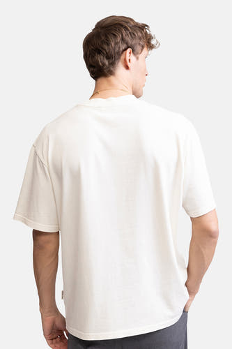 T-shirt écru à manches courtes de REDEFINED REBEL, dos, avec chaîne subtile et pantalon foncé.