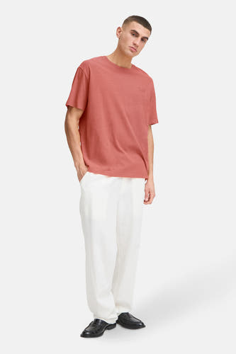 T-shirt rouge à manches courtes de SOLID, porté avec un pantalon blanc et des chaussures noires.