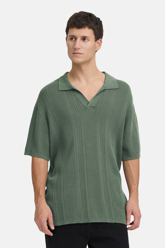 T-shirt vert de SOLID, avec des manches courtes et un col V, porté avec un pantalon noir et des chaussures marron.