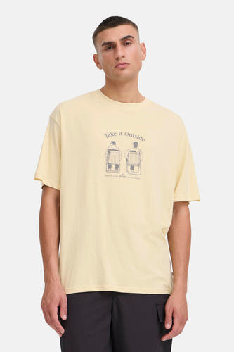 T-shirt à manches courtes jaune de SOLID, avec un imprimé sur le devant, porté avec un pantalon noir et des baskets.