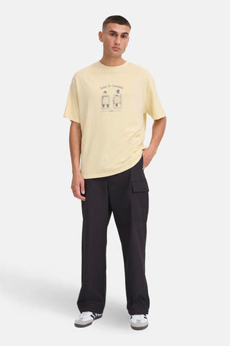 Geel T-shirt met korte mouwen van SOLID, met een print op de voorkant, gedragen met zwarte broek en sneakers.
