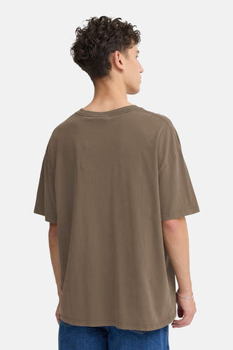 T-shirt brun à manches courtes de SOLID, vu de dos, avec un pantalon de travail et un bracelet en argent.