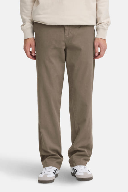 Jean chino marron de SOLID, porté avec un pull beige et des baskets blanches à rayures noires.