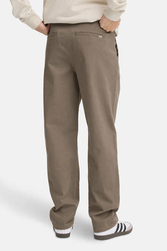 Jean chino marron de SOLID, vu de l'arrière, avec un pull beige et des baskets Adidas Samba.
