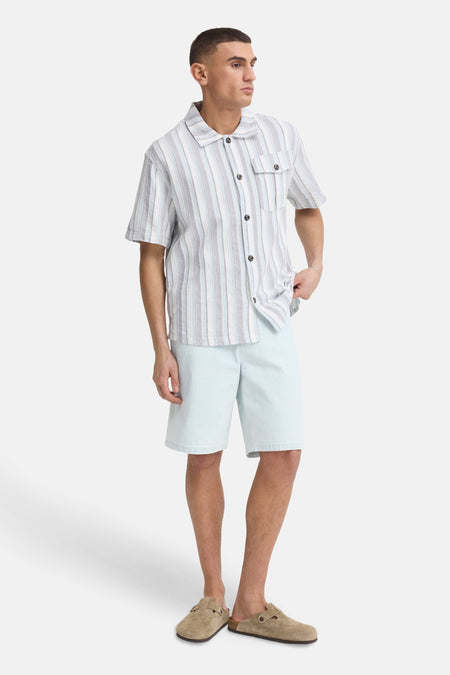 Lichtblauwe denim shorts van SOLID, rechte pasvorm, gedragen met gestreept overhemd en bruine slippers, volledige vooraanzicht.