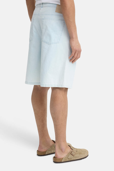 Lichtblauwe denim shorts van SOLID, achterzijde met twee zakken, model draagt beige slippers, zijprofiel