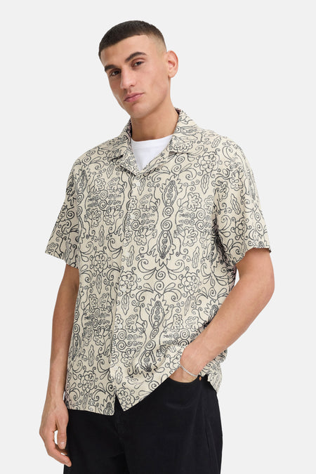 Chemise écru à manches courtes de SOLID, avec motif organique foncé et col ouvert, portée sur un t-shirt blanc.