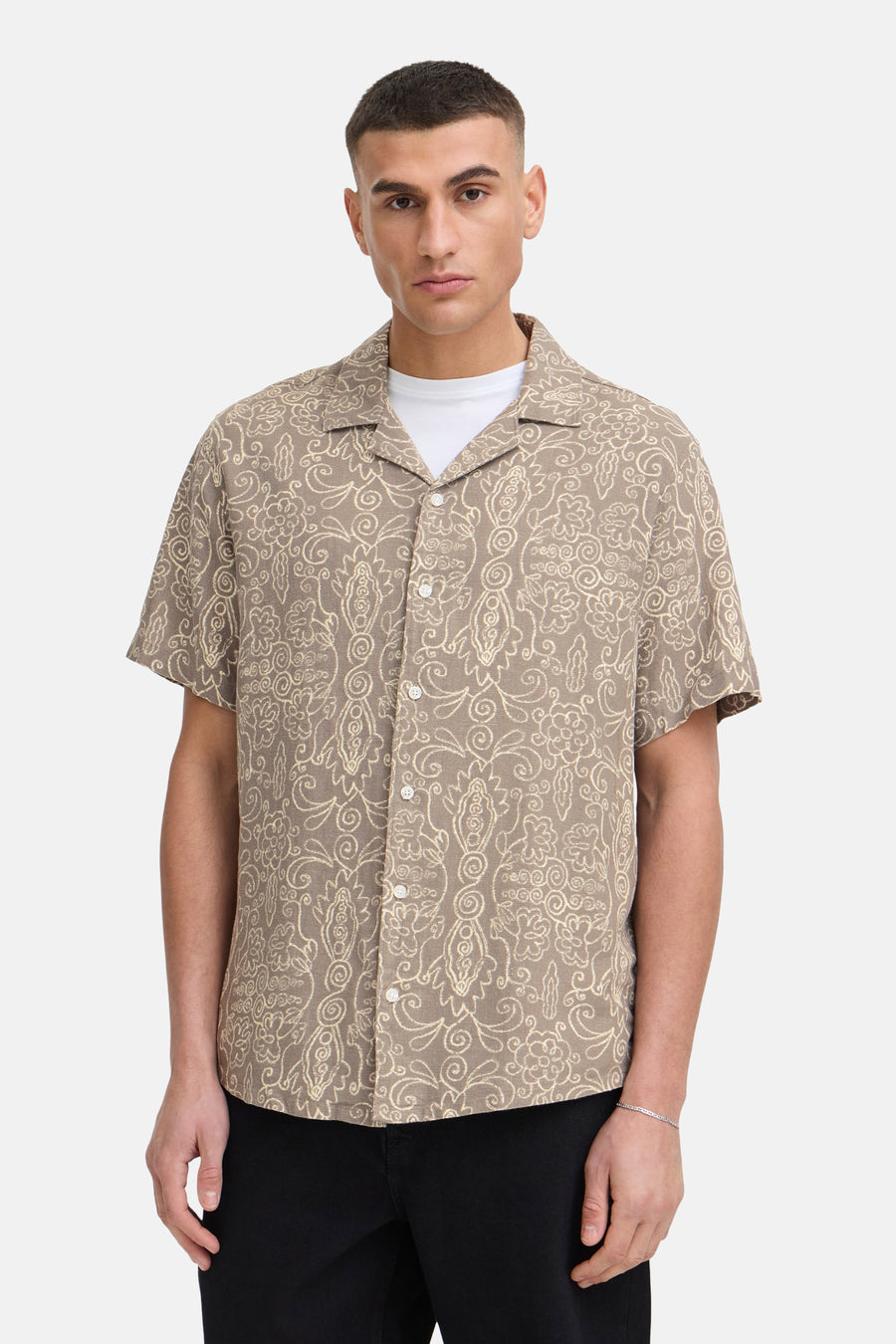Chemise marron à manches courtes de SOLID, avec un motif floral et feuillage crème, portée sur un t-shirt blanc.