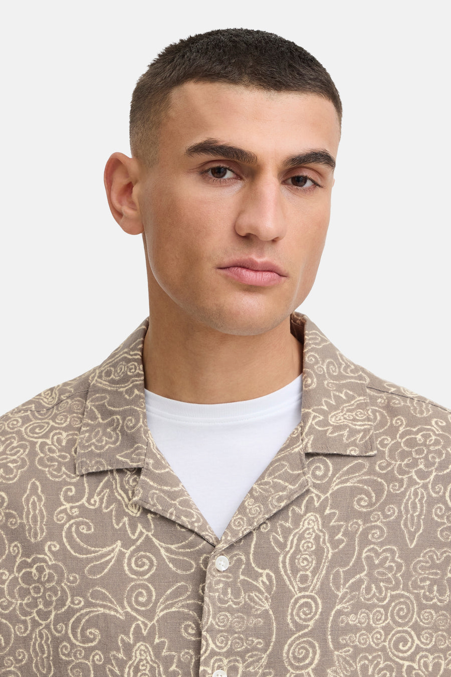 Bruin hemd met korte mouwen van SOLID, met een crème bloemen- en bladmotief, gedragen over een wit T-shirt.