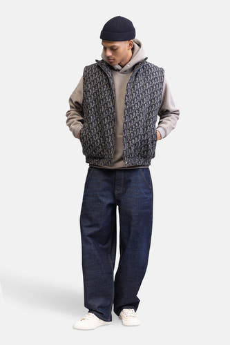 Pull-over beige avec capuche Redefined Rebel, porté avec une chemise à motif, des jeans larges et des baskets blanches.