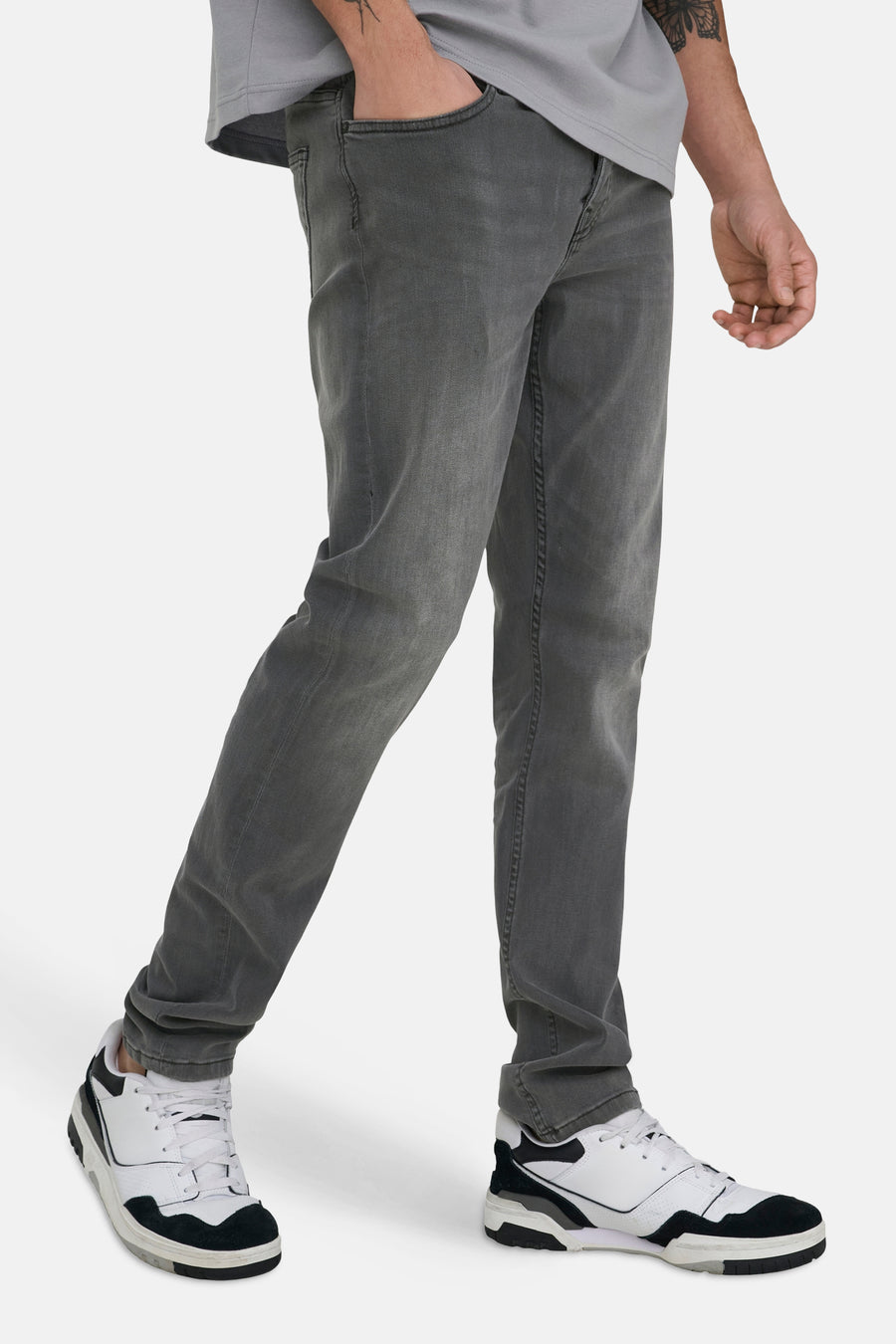 Jean slim fit gris foncé de ONLY & SONS®, avec délavage usé et associé à des baskets blanches.