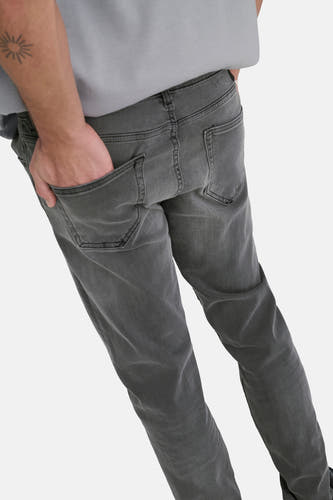 Jean slim fit gris foncé de ONLY & SONS, avec poches arrière et une main dans la poche.