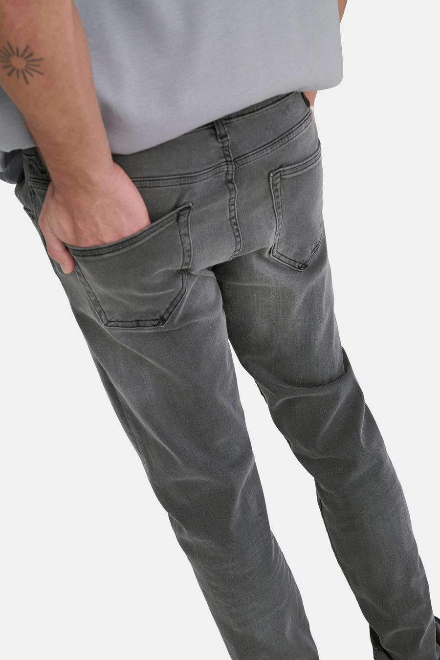 Jean slim fit gris foncé de ONLY & SONS, avec poches arrière et une main dans la poche.