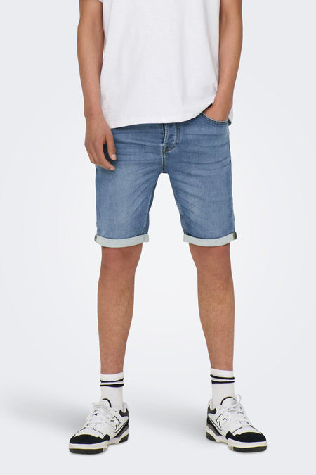 Jean court en denim bleu clair d'ONLY & SONS, avec des poches rabattues, associé à un T-shirt blanc, des chaussettes blanches et des baskets.