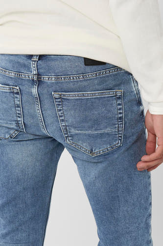 Jean slim fit en denim mid blue, ONLY & SONS®, avec une poche arrière et un haut blanc.