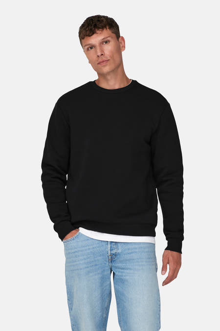 Pull-over noir d'ONLY & SONS, porté avec un T-shirt blanc et des jeans bleu clair.