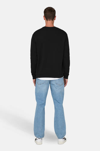 Pull-over noir d'ONLY & SONS, avec un col rond, porté sur une chemise blanche et associé à des jeans larges et des baskets blanches.