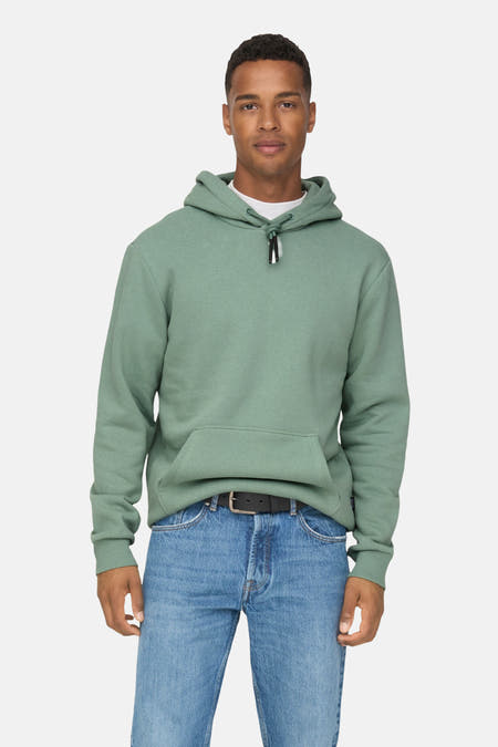Pull-over vert de ONLY & SONS® avec capuche, porté avec un jean bleu et des baskets blanches.