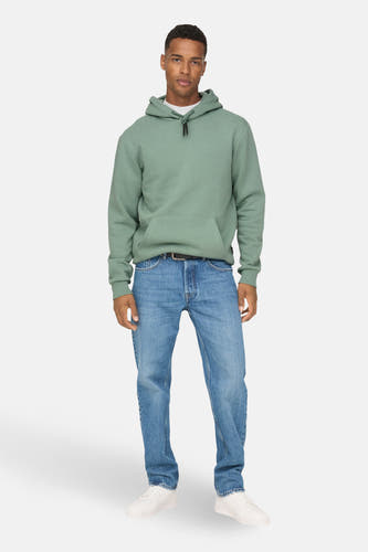 Groene sweater met kap van ONLY & SONS®, gedragen met een blauwe jeans en witte sneakers.