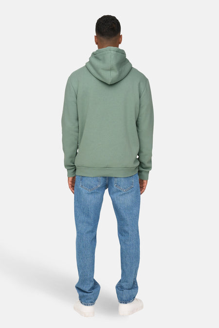 Een man van achteren in een groene hoodie en blauwe spijkerbroek.